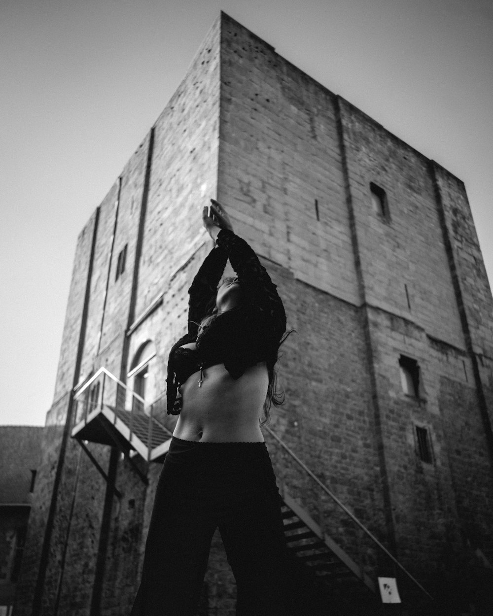 a woman standing in front of a tall brick building