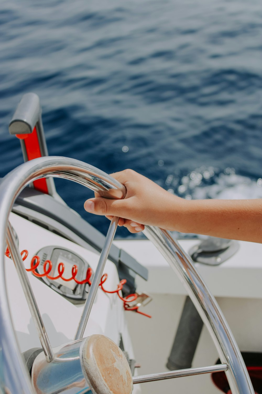 a hand on the steering wheel of a boat