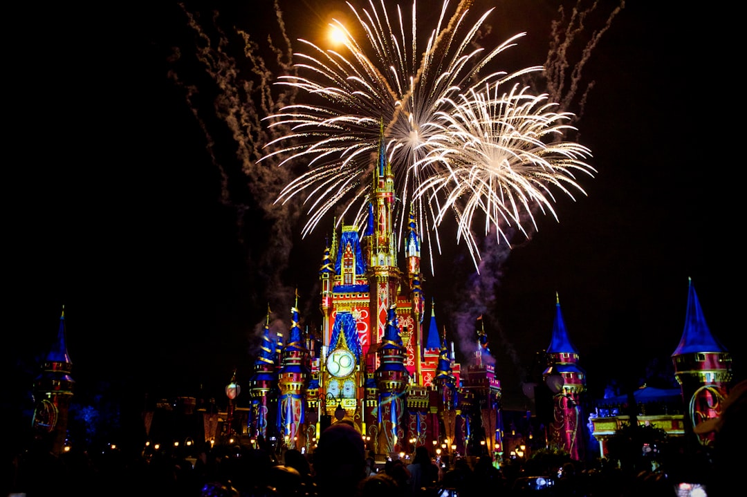 a castle is lit up with fireworks at night, Fireworks and colorful projections on Cinderella Castle during one of the fi