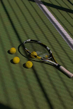 a tennis racket and four tennis balls on a court