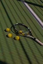 a tennis racket and four tennis balls on a court