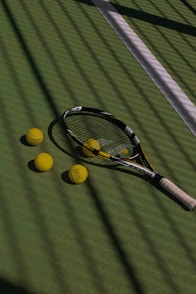 a tennis racket and four tennis balls on a court