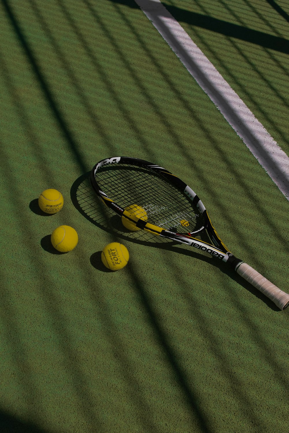 a tennis racket and four tennis balls on a court