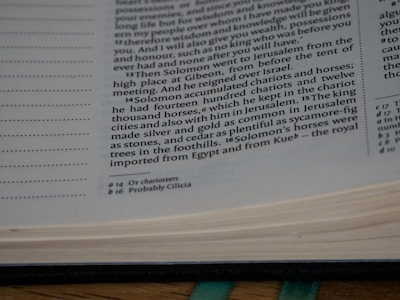 The image shows a close-up of a page from a book, specifically a biblical text. The text discusses Solomon accumulating chariots and horses. There are footnotes at the bottom of the page detailing additional information.