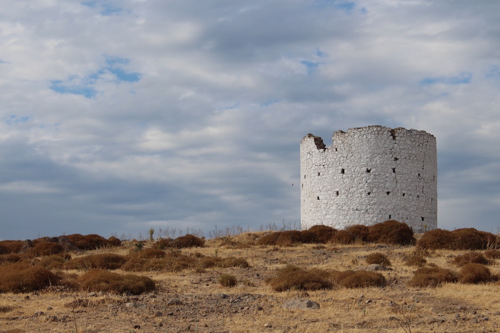 a tall white tower sitting on top of a dry grass field