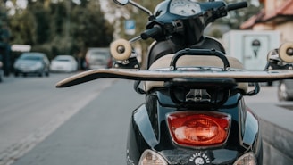 A compact GPS tracker mounted on a two-wheeler parked near a busy urban street.
