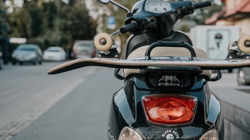 A compact GPS tracker mounted on a two-wheeler parked near a busy urban street.