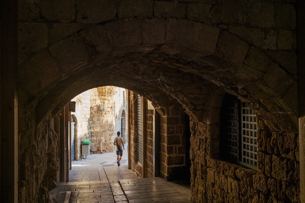 a man is walking down a narrow alley way