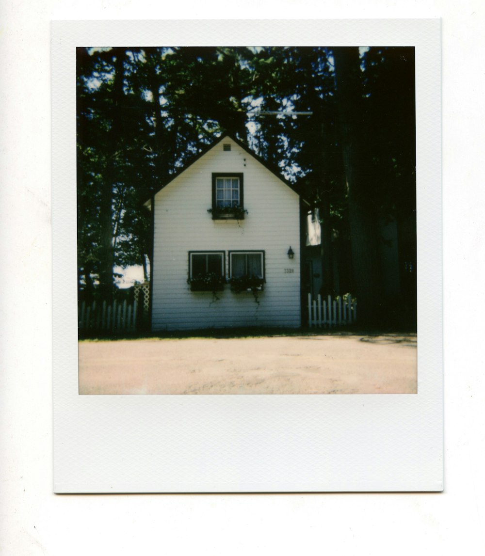 uma imagem de uma casa branca com árvores no fundo