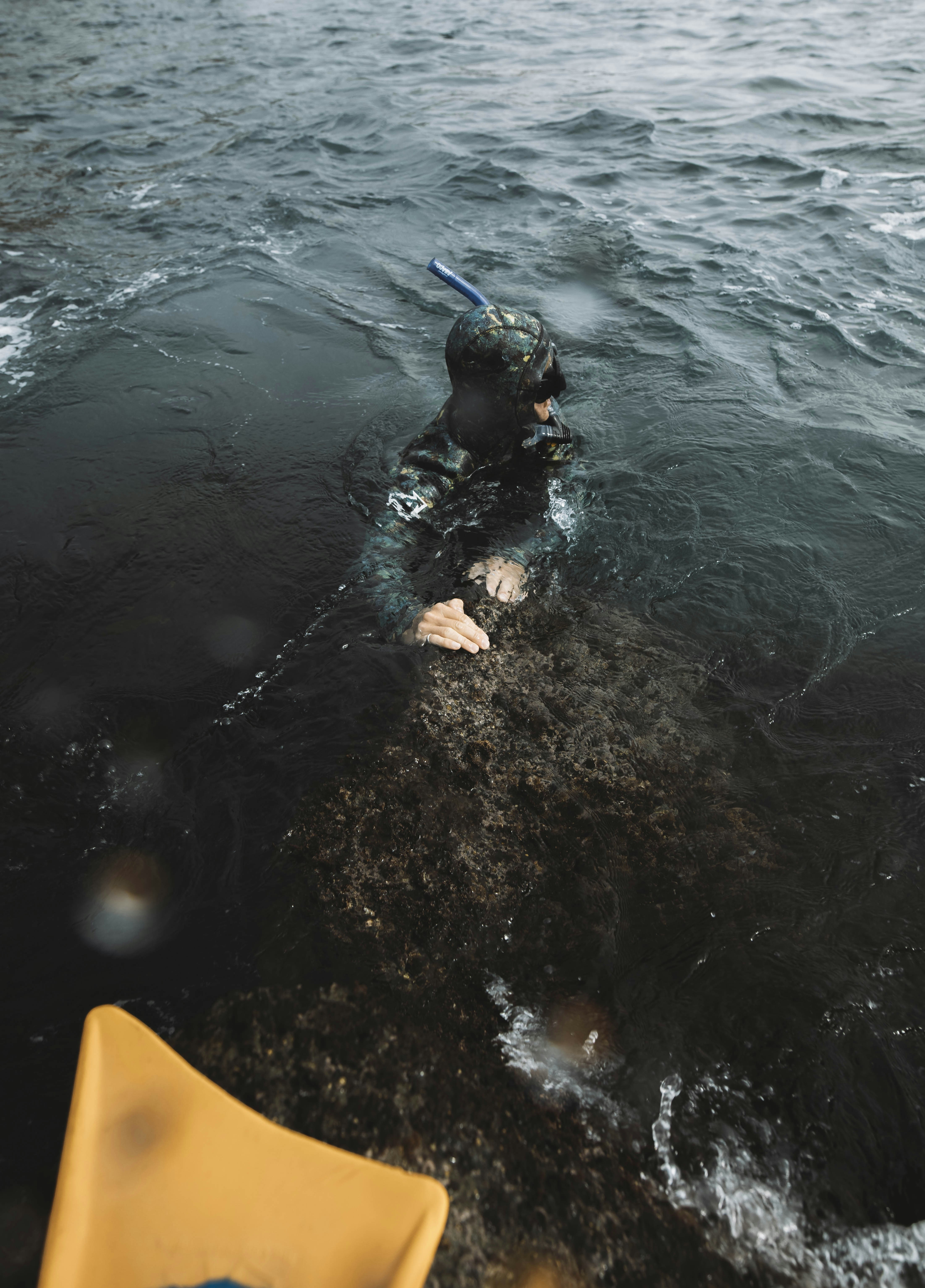 a man in a wet suit swimming in a body of water
