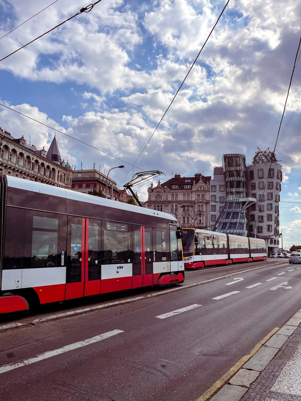 Ein rot-weißer Zug fährt eine Straße neben hohen Gebäuden entlang