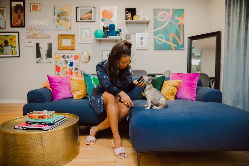 Eine Frau, die auf einer blauen Couch sitzt und einen Hund hält