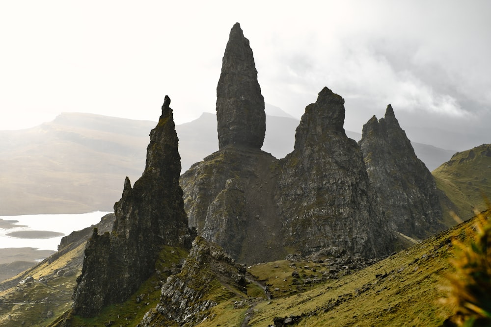 a group of tall rocks sitting on top of a lush green hillside