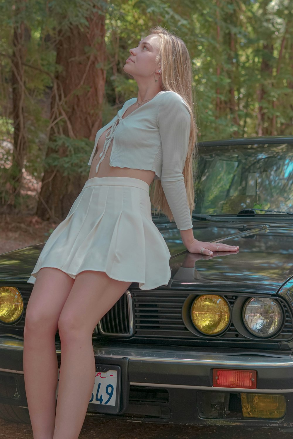 a woman leaning on the hood of a car