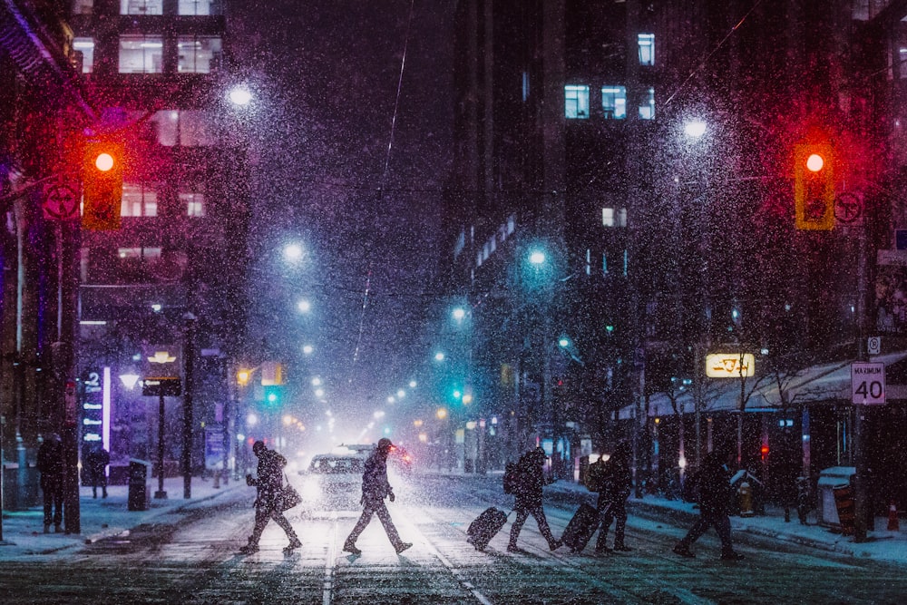 a group of people crossing a street at night