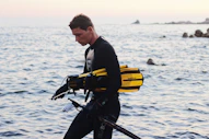 a man in a wet suit is walking along the water