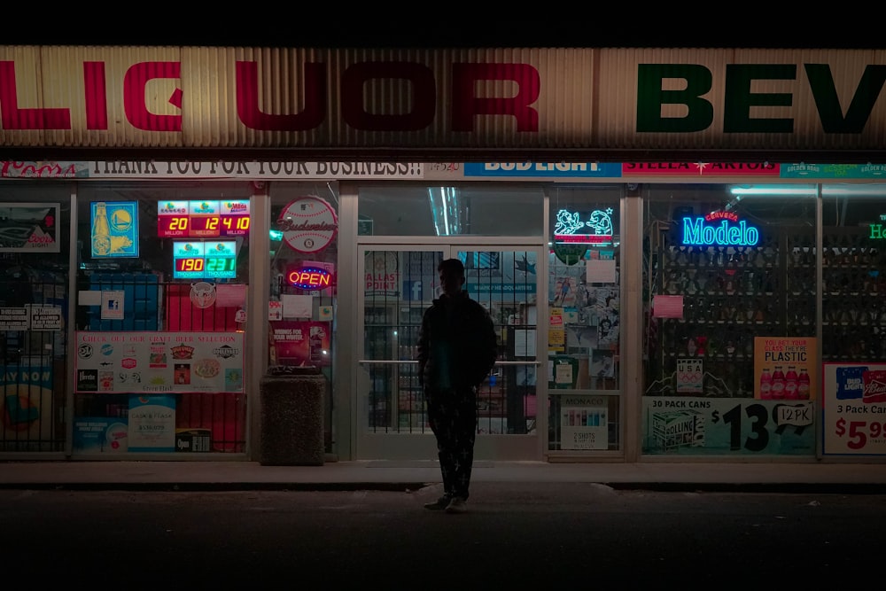 a man standing in front of a liquor store at night