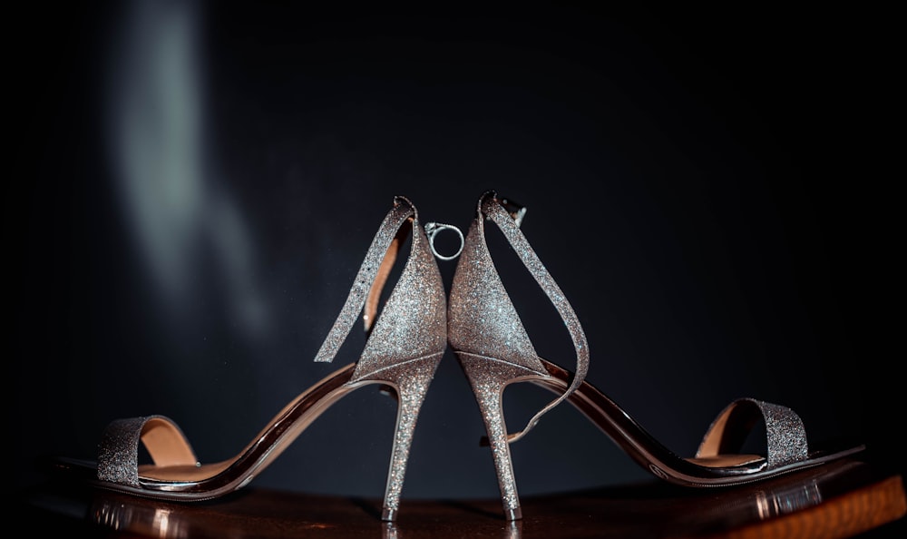 a pair of silver high heeled shoes sitting on top of a table