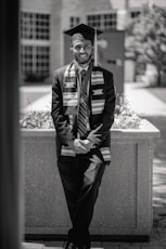a black and white photo of a man in a graduation gown
