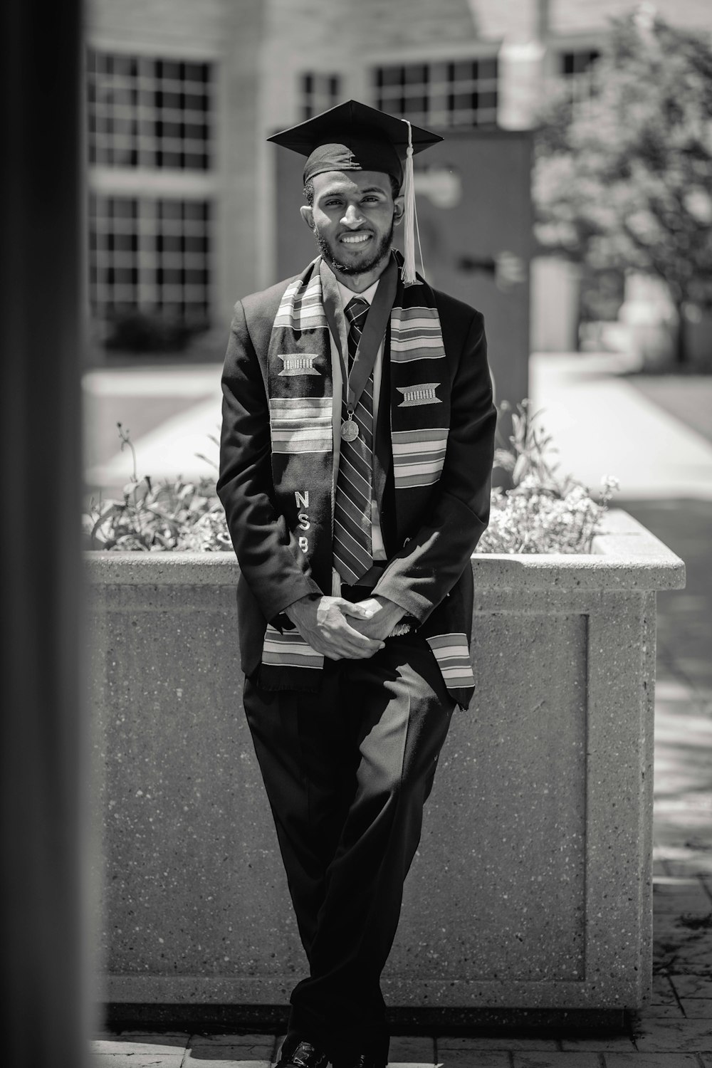 a black and white photo of a man in a graduation gown