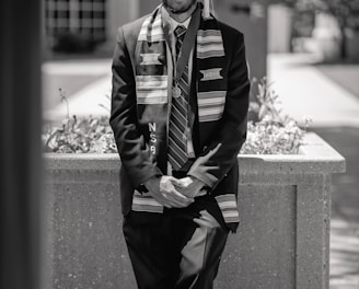 a black and white photo of a man in a graduation gown