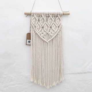a macrame hanging on a wall with a tag