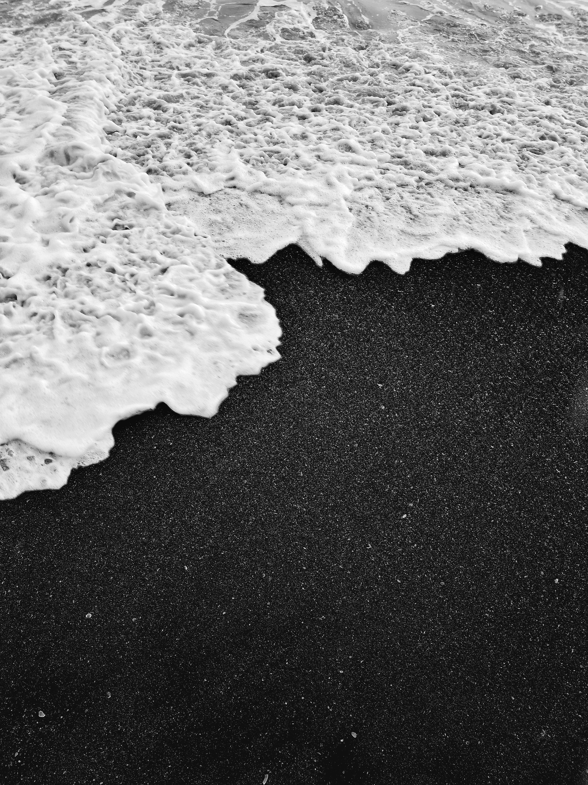 a black sand beach with a wave coming in