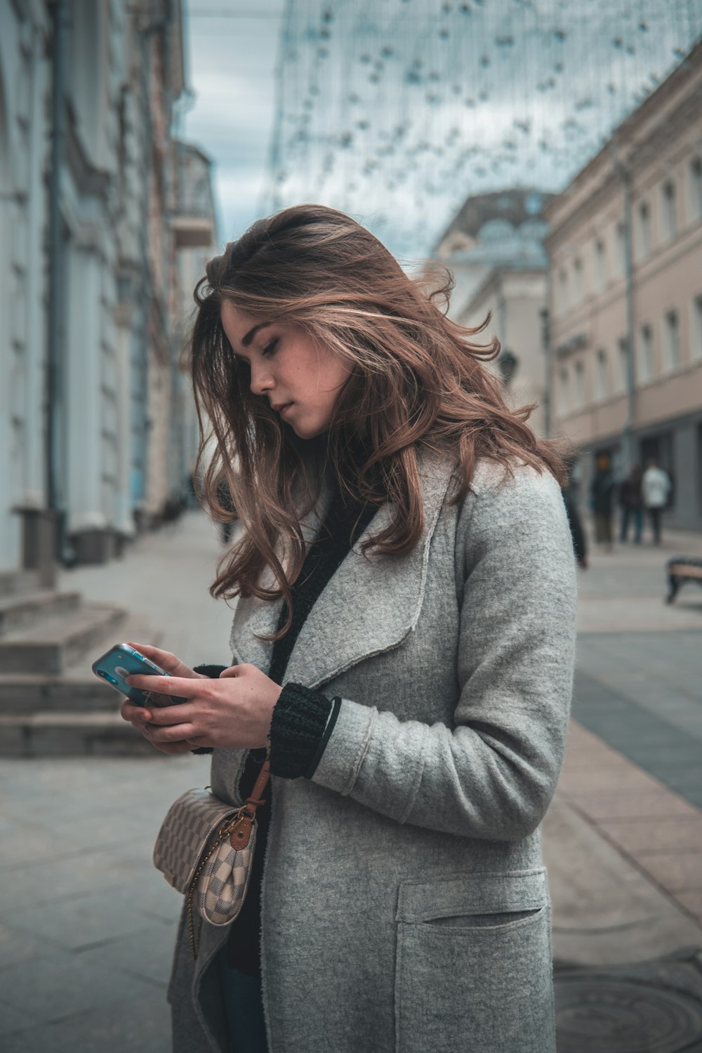 uma mulher em pé em uma rua olhando para seu telefone celular