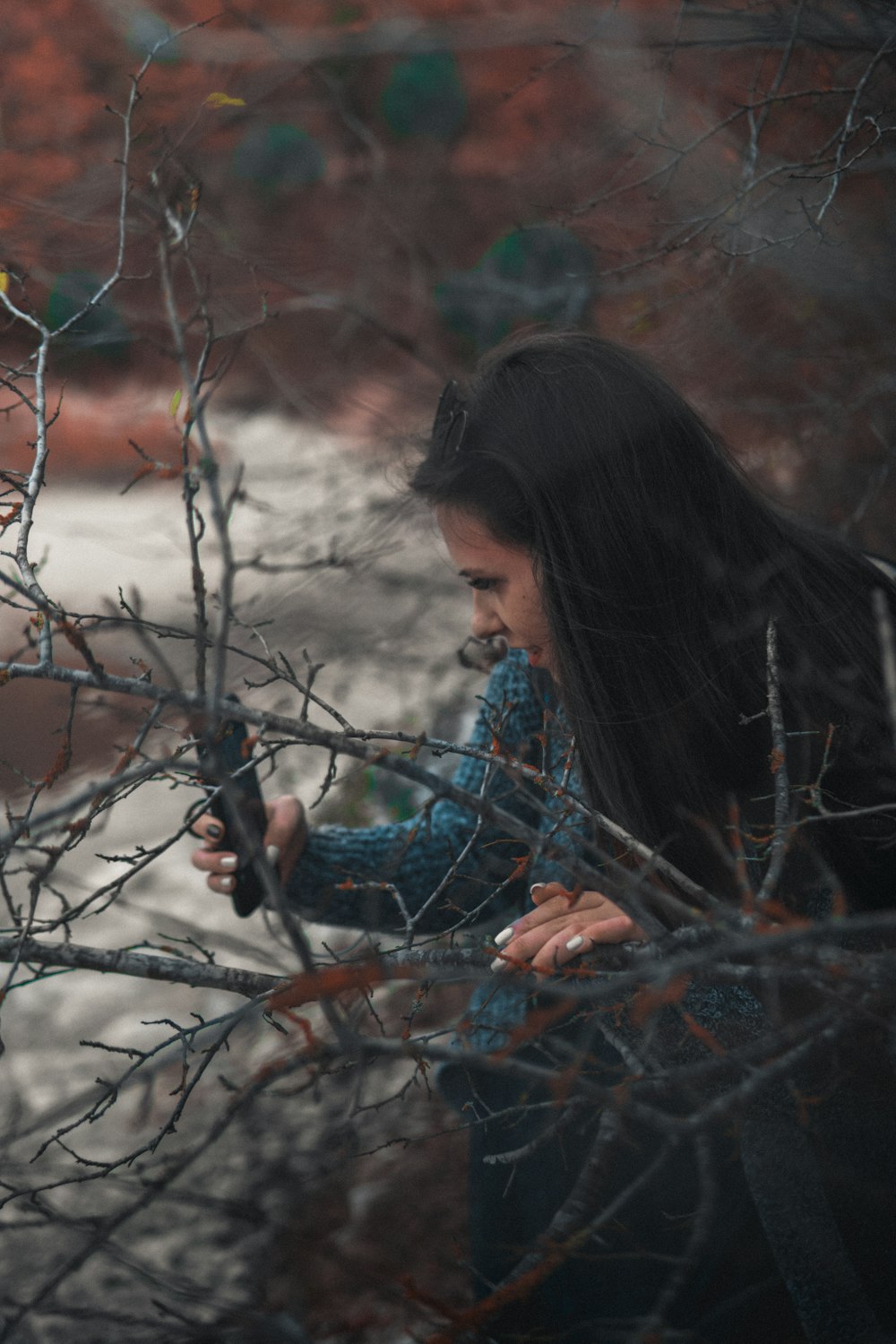 a woman standing next to a tree holding a cell phone