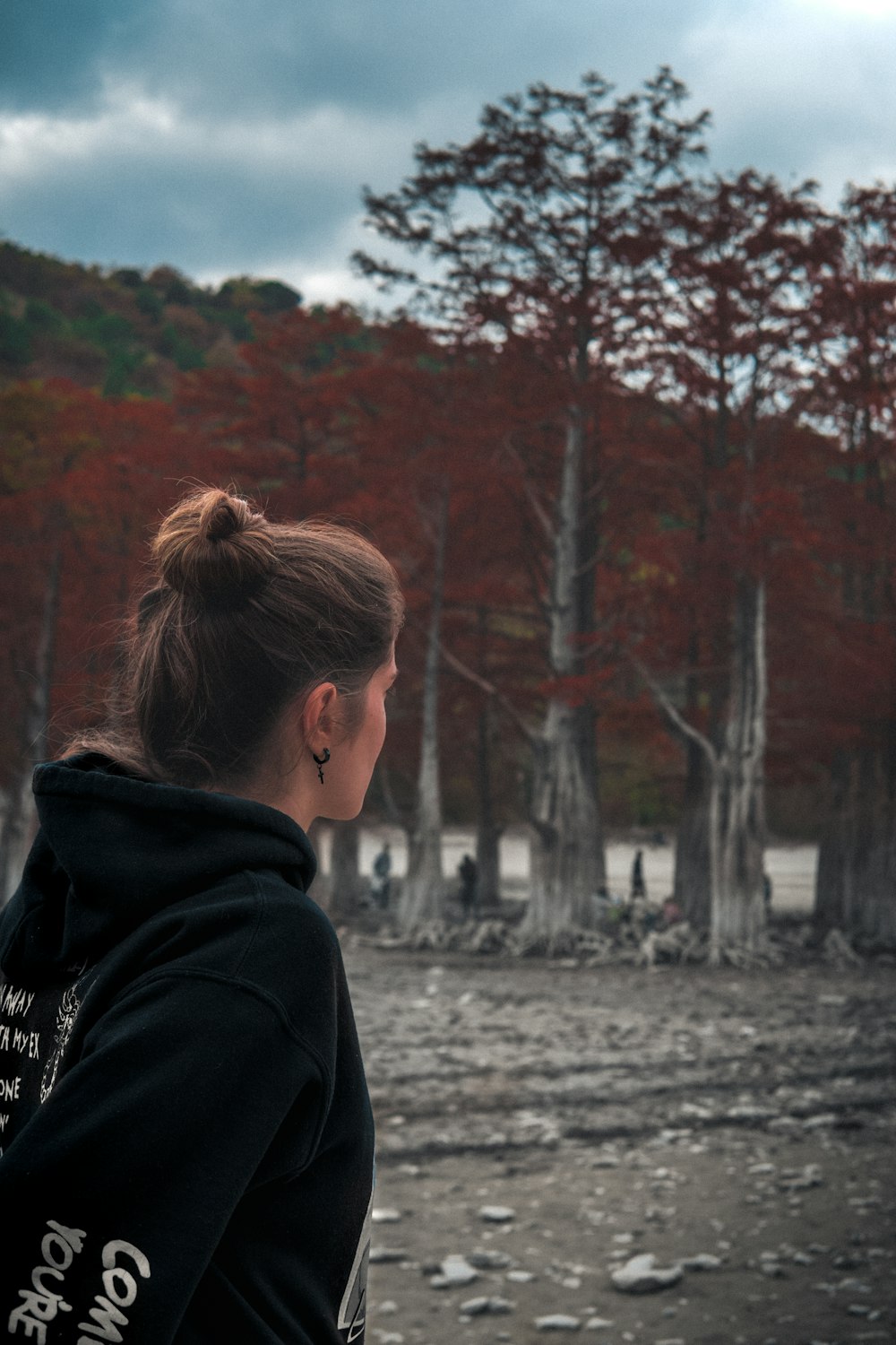 a woman in a black hoodie looking at a forest