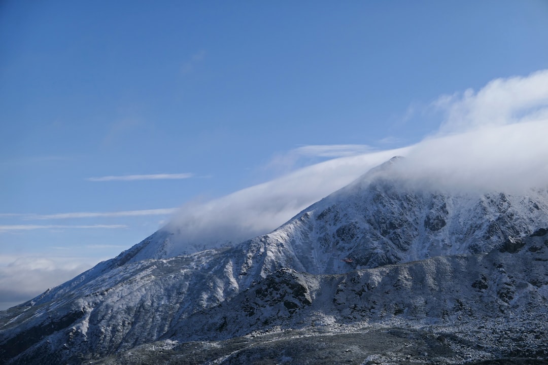 a mountain covered in snow under a blue sky,