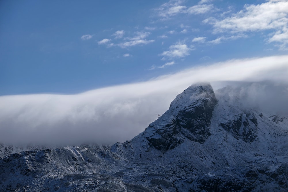 a mountain covered in snow under a cloud filled sky