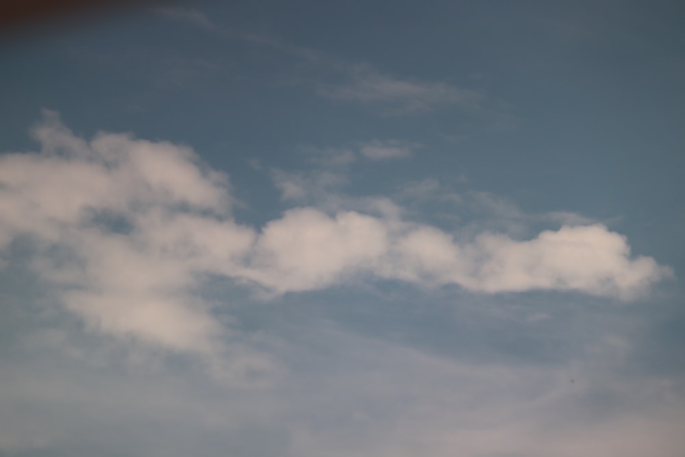 Un avión volando a través de un cielo azul nublado