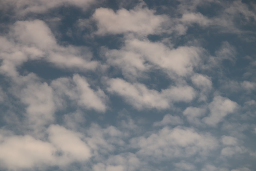 Un avión volando a través de un cielo azul nublado