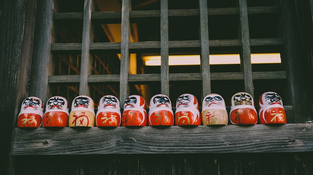 a row of red and yellow japanese dolls on a wooden fence