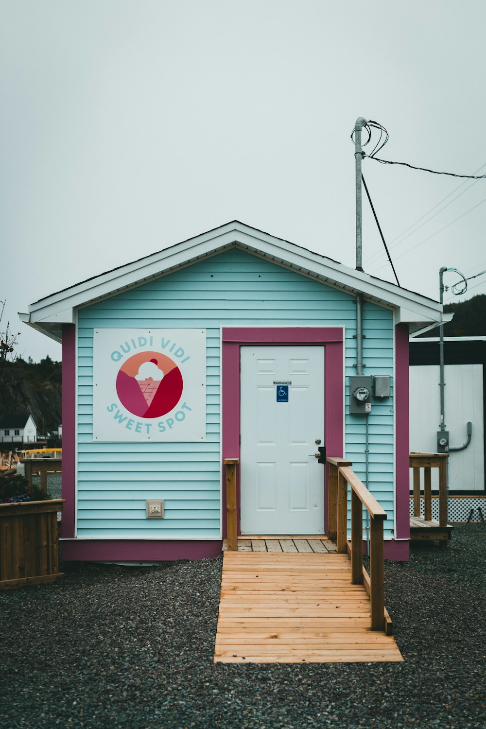 a small blue building with a red and white door