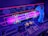 A close-up view of a retro-style arcade game interface, featuring a neon-lit control panel with vibrant purple and blue lights. A translucent blue joystick with a red button is positioned on the right side, surrounded by various geometric designs and arrows on the surface. The control panel includes instructions and two round yellow buttons.