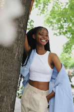 a woman standing next to a tree smiling