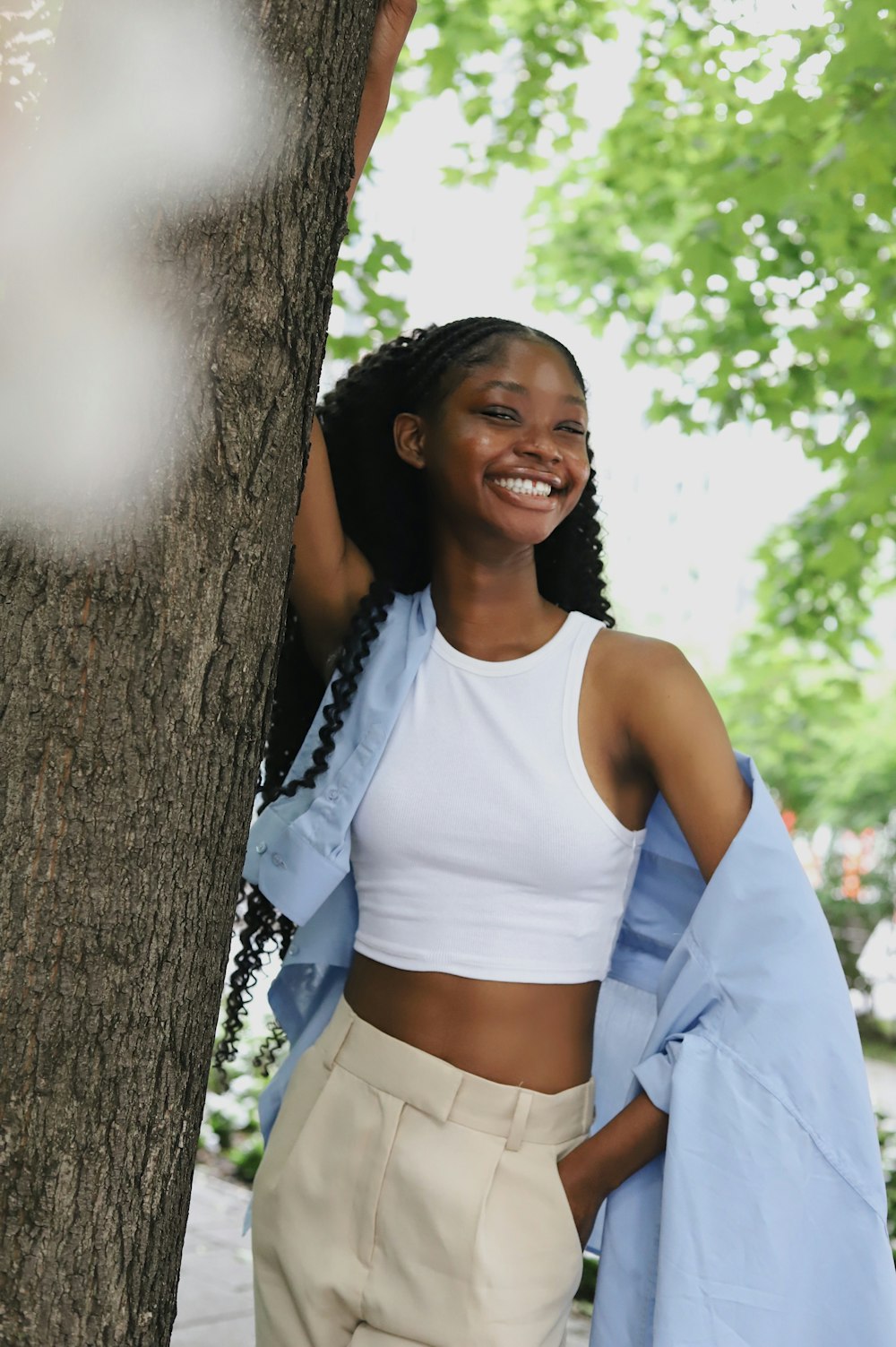 a woman standing next to a tree smiling