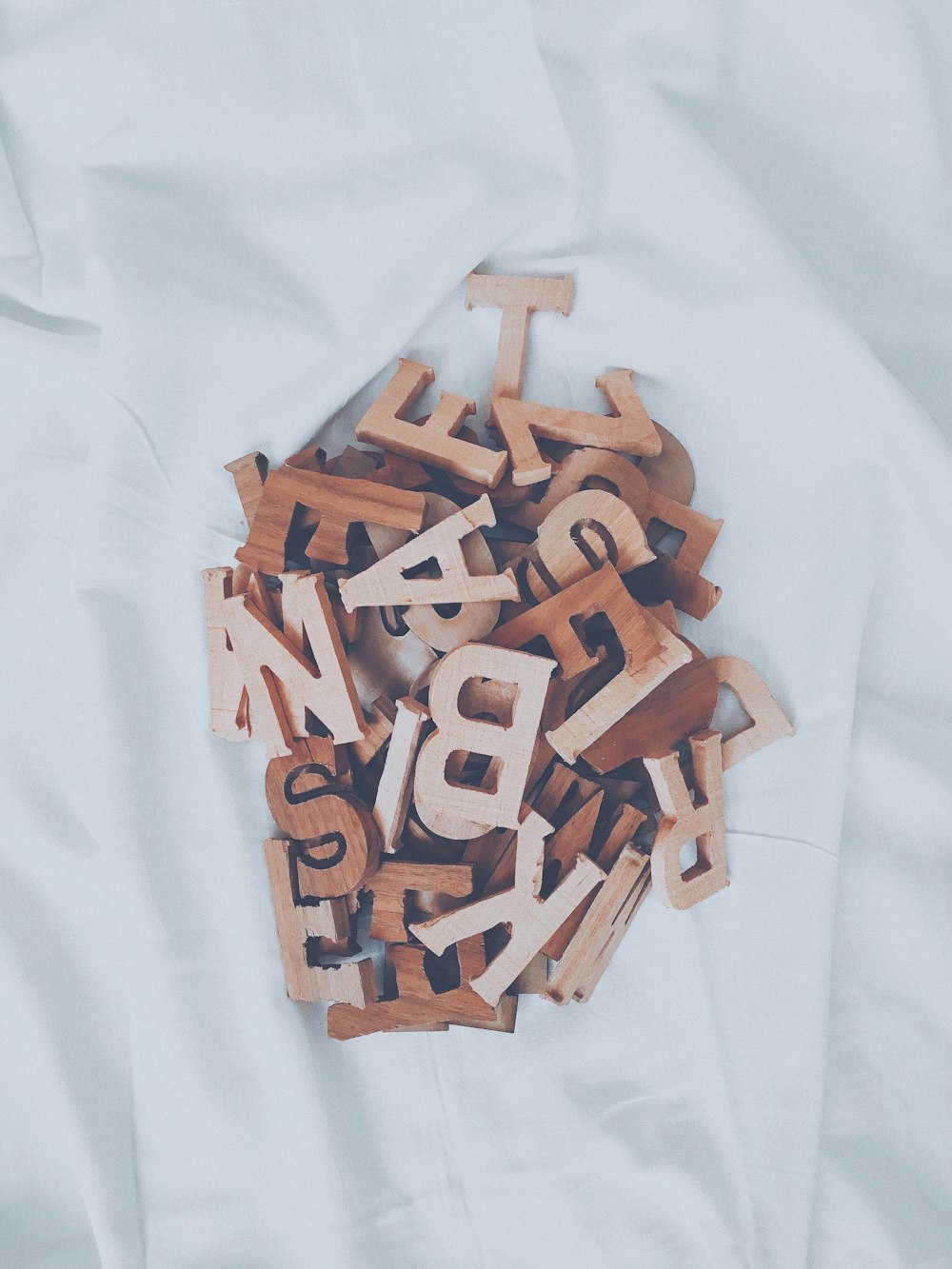 uma pilha de letras de madeira sentada em cima de um lençol branco