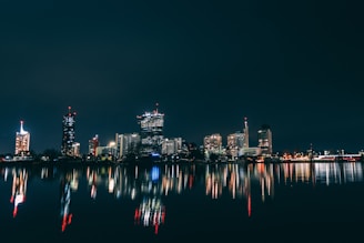 a city skyline is reflected in the water at night