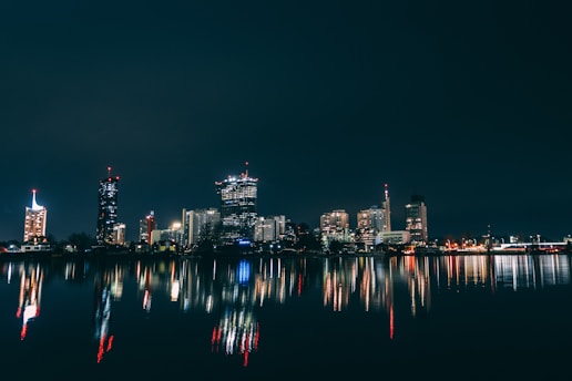 a city skyline is reflected in the water at night