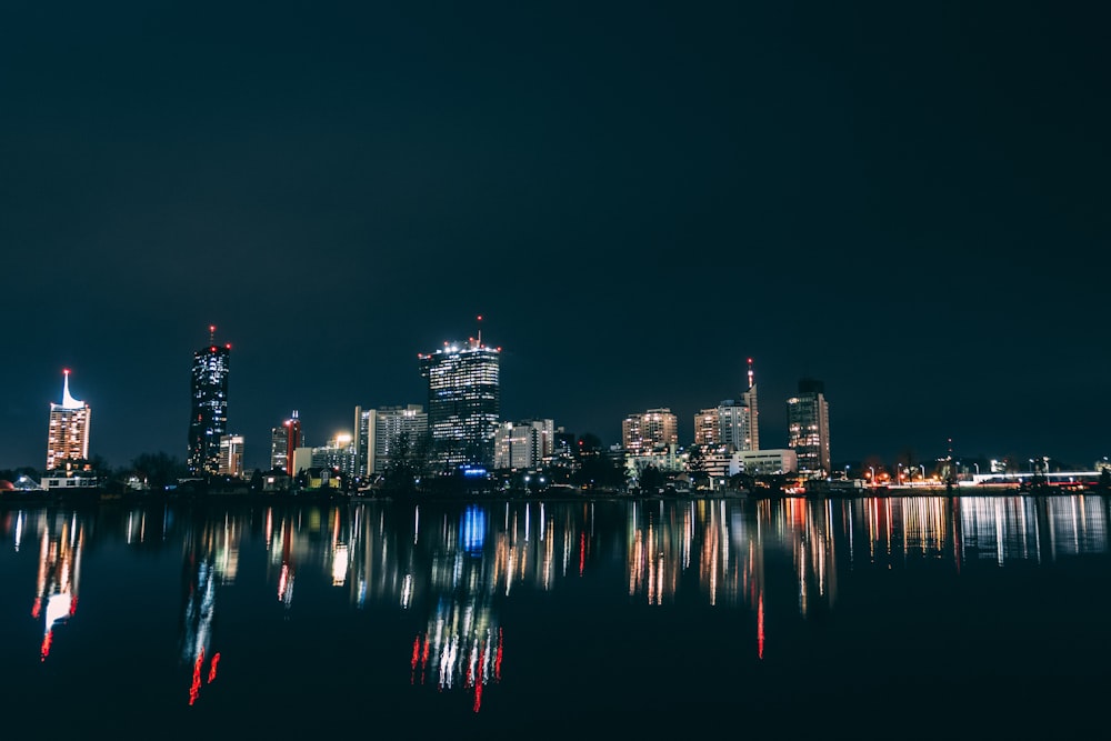 a city skyline is reflected in the water at night