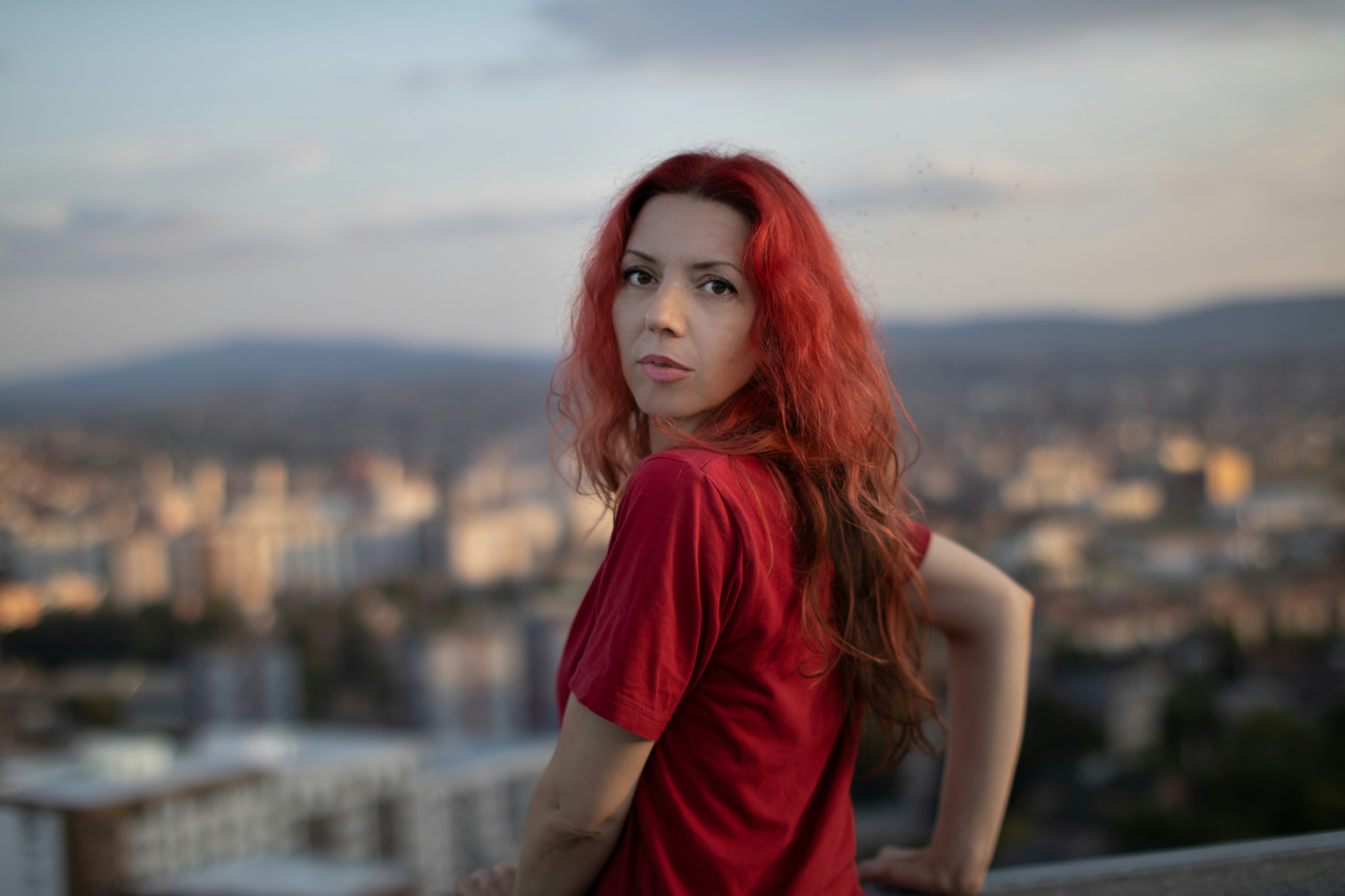 a woman with red hair standing in front of a cityscape