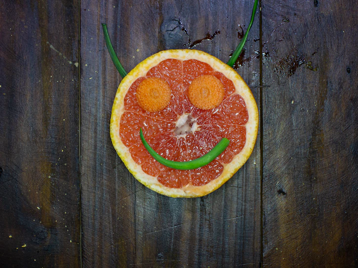 A colorful plate filled with kid-friendly, bite-sized vegetable snacks arranged like a smiling face.