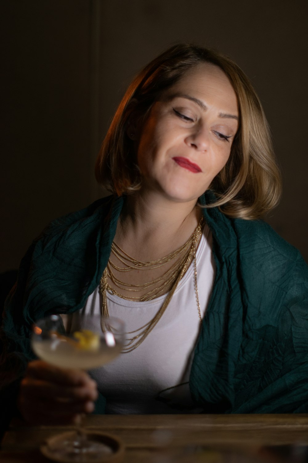 a woman sitting at a table holding a wine glass
