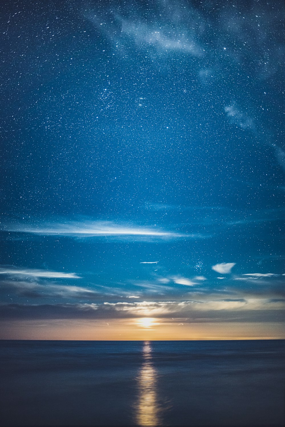 a view of the ocean at night with stars in the sky