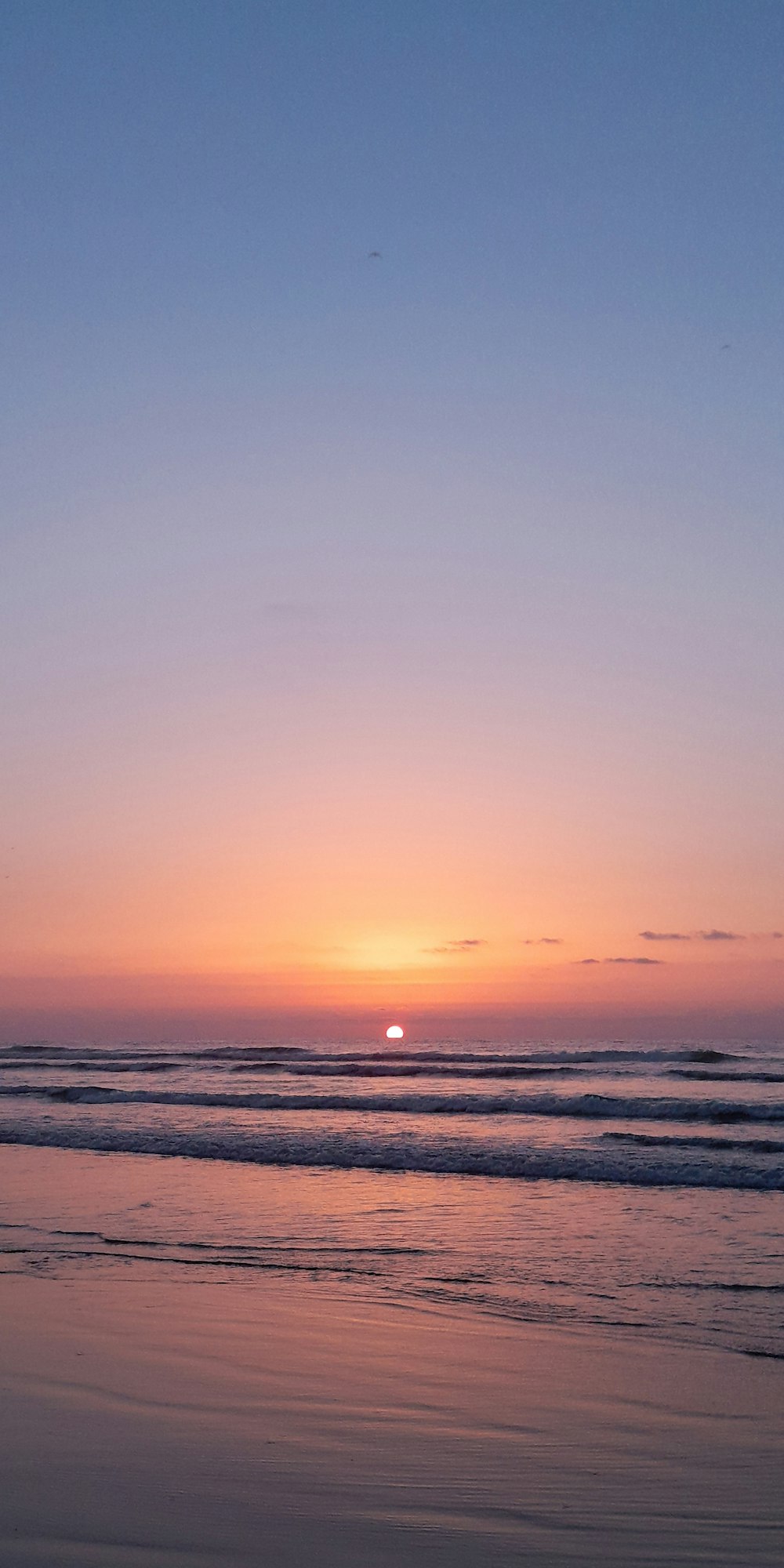 the sun is setting over the ocean on the beach