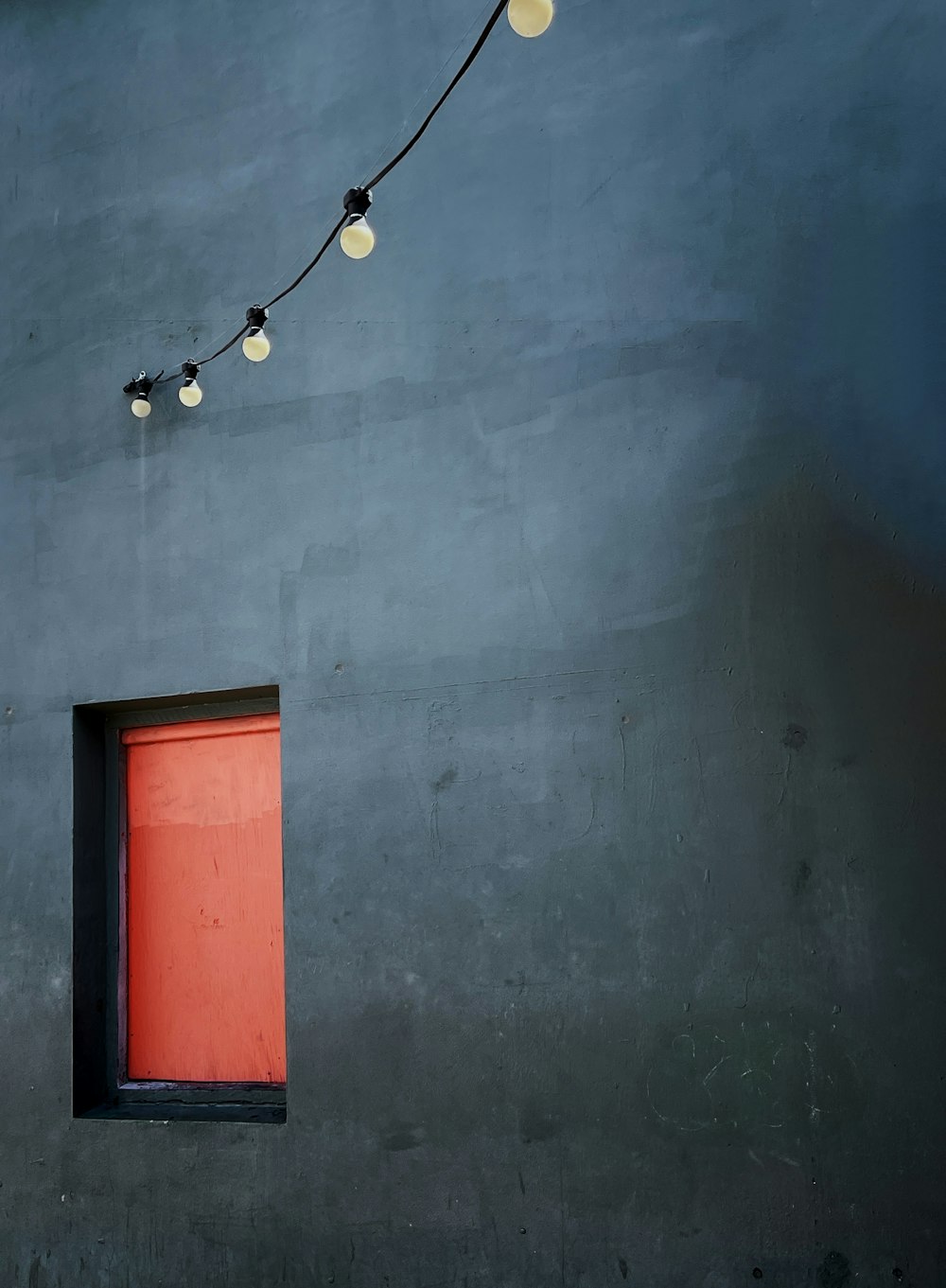 a red door and some lights on a gray wall
