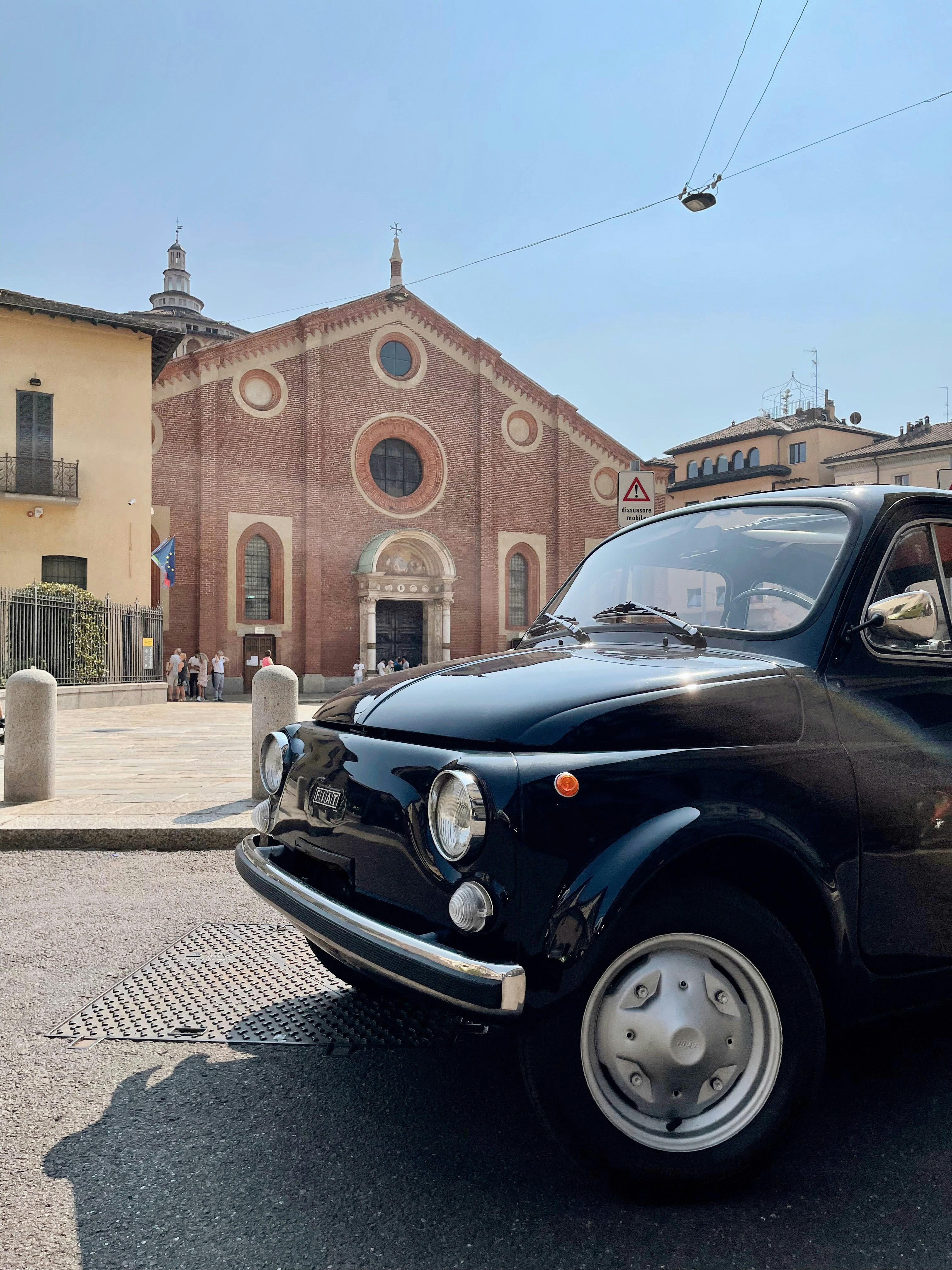 Une petite voiture noire garée devant une église